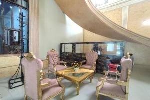 um quarto com cadeiras cor-de-rosa, uma mesa e um espelho em ZAHIRA GUESTHOUSE em Palmerah