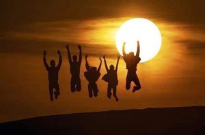 um grupo de pessoas pulando na frente do sol em Excellent Desert Safari camp em Sām