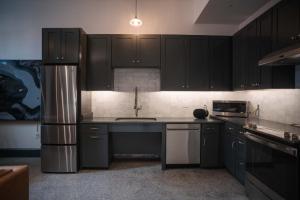 uma cozinha com armários pretos e um frigorífico de aço inoxidável em The Mary Beth Hotel & Gallery em Nova Orleans