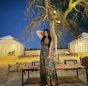 a woman in a dress standing next to a tree at Excellent Desert Safari camp in Sām