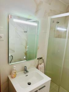 een badkamer met een wastafel, een spiegel en een douche bij Sweet Sleep Apartment in Lissabon