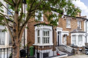 a brick house with a fence and a tree at The Hammersmith Villa in London