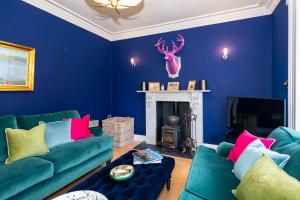 een blauwe woonkamer met twee groene banken en een open haard bij Rosebank House - 12 Guests, 6 Ensuite Bedrooms, EV point, Games Rooms, Wood Burner, Pet Friendly! in Blairgowrie