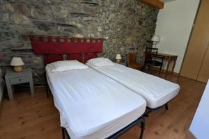 a large bed in a room with a stone wall at Gîte Neige Cordier - Villar d'Arène center 2 bedrooms and large terrace in Villar-dʼArène