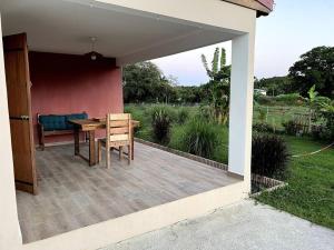 eine Terrasse mit einem Holztisch und Stühlen auf einer Veranda in der Unterkunft Jolie petite maison à la campagne in Le Moule