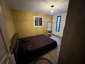 1 dormitorio con cama y pared amarilla en Jolie petite maison à la campagne, en Le Moule