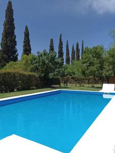una piscina azul con árboles en el fondo en Cabaña sol y campo en Guaymallén