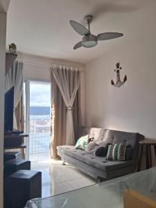 a living room with a couch and a ceiling fan at Apto aconchegante beira mar com ar no quarto in Solemar