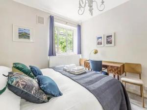 a bedroom with a bed with blue pillows and a desk at Pass the Keys Battersea Hideaway in London