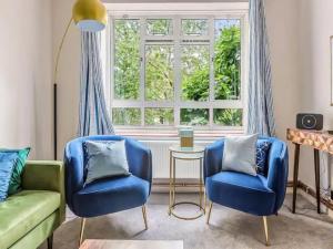 a living room with two blue chairs and a window at Pass the Keys Battersea Hideaway in London