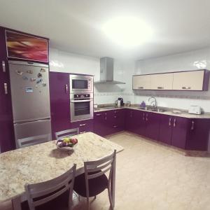 a kitchen with purple cabinets and a table with a bowl of fruit on it at Playa de Levante, Céntrico, AC, Wifi y Parking - by Aloha Palma in Águilas