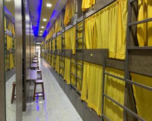 una fila di tavoli in un corridoio con tende gialle di Neenava Dormitory Asalpha a Mumbai