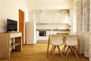 a kitchen with white cabinets and a table and two chairs at Windmill 2 Bed Apartment in Odiaxere in Odiáxere