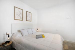 een witte slaapkamer met een wit bed met een knuffeldier erop bij El Ramonal Vacacional in Candelaria