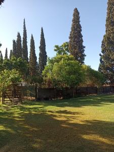 un campo de césped con árboles y una valla en Cabaña sol y campo en Guaymallén