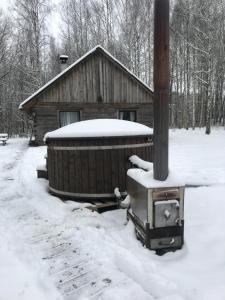 a log cabin with snow on the ground next to a stove at Pirts Muzejs 