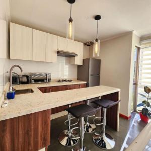 a kitchen with a counter and two bar stools at Departamento para 4 personas en 2° piso. in Talca