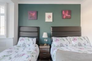 two beds in a bedroom with blue walls at Room in Guest room - Apple House Wembley - Family room with shared bathroom in Edgware