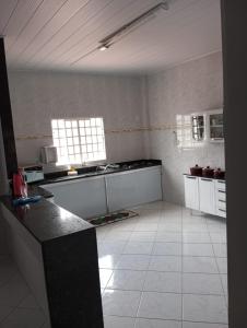 uma grande cozinha com pisos em azulejos brancos e uma bancada em Vista da Serra em Cavalcante