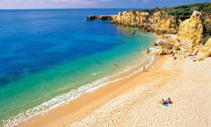 a group of people on a beach near the water at The Albufeira Concierge - Modern Salgados in Albufeira