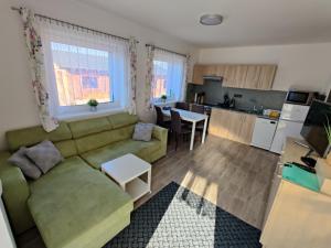ein Wohnzimmer mit einem grünen Sofa und einer Küche in der Unterkunft Apartmán Anamo in Vrchlabí