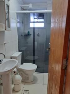 a bathroom with a toilet and a sink and a shower at Apto aconchegante beira mar com ar no quarto in Solemar