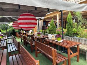 a restaurant with wooden tables and benches under a canopy at Sportalm Gipfelglück in Lüdenscheid