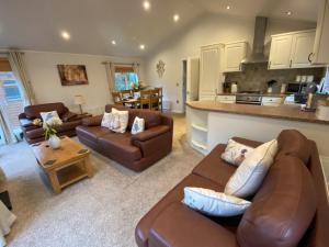 a living room with brown leather furniture and a kitchen at 3 Bed in Okehampton 49134 in Okehampton