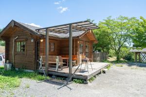 Cabaña pequeña con porche, mesa y sillas en BIO-RESORT HOTEL & SPA O Park OGOSE, en Ogose