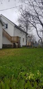a large white building with a wooden bench in a field at Lofoten - Koselig leilighet for 3 personer. in Sund