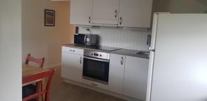 a kitchen with white cabinets and a refrigerator and a table at Lofoten - Koselig leilighet for 3 personer. in Sund
