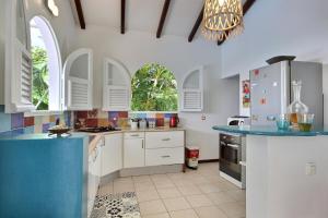 a kitchen with white cabinets and blue counter tops at Palmier Rouge in Sainte-Luce