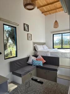 a room with a couch and a bed with windows at Corinto Tiny House in Paipa