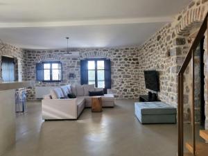 sala de estar con sofá blanco y pared de piedra en VillaAurora-mani, en Areopoli