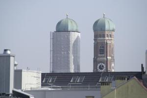 um edifício com uma torre de relógio e dois edifícios altos em Hotel Demas City em Munique