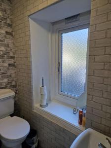 baño con ventana, aseo y lavamanos en Ideal for short stays en Cork