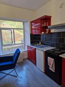 a kitchen with red cabinets and a blue chair in it at Ideal for short stays in Cork