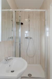 uma casa de banho branca com um chuveiro e um lavatório. em Room in Guest room - Family room with private bathroom em Edgware
