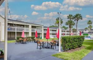 a patio with tables and chairs with red umbrellas at Pool - WiFi - Gym - Parking - Best Location ! in Kissimmee