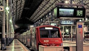 a red train is pulling into a train station at April Square by Lisbon with Sintra in Amadora