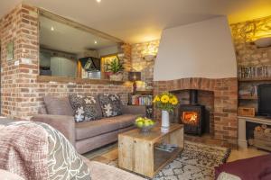 sala de estar con sofá y chimenea en Cog Cottage 2, en Little Walsingham