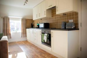 a kitchen with white cabinets and a stove top oven at Laburnum Maisonettes by Oracle in Stratford-upon-Avon
