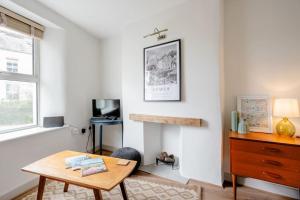 a living room with a wooden table and a desk at Cosy cottage near the coast in Tywardreath