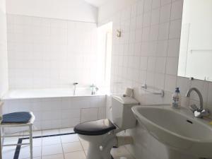 La salle de bains blanche est pourvue de toilettes et d'un lavabo. dans l'établissement Le Prieuré Saint Blaise, à Le Puy-Saint-Bonnet