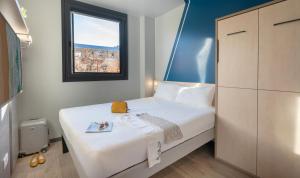 a small bedroom with a bed and a window at ibis budget Valencia Centro Puerto in Valencia