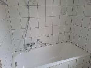 La salle de bains carrelée de blanc est pourvue d'une douche et d'une baignoire. dans l'établissement Plapperer`s Fewo, à Schernfeld