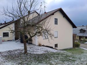 Una casa blanca con un árbol delante. en Plapperer`s Fewo en Schernfeld