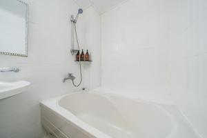 a white bathroom with a tub and a sink at Jeju B Hotel in Jeju
