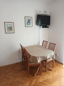 una sala da pranzo con tavolo, sedie e TV di Vila Bozica a Jadranovo