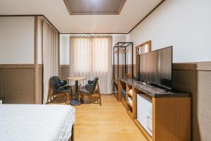 a hotel room with a bed and a flat screen tv at Jeju B Hotel in Jeju